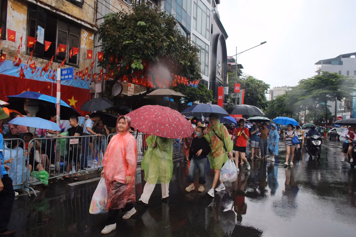 Nhiều người đội mưa đi tìm chỗ xem diễu binh.