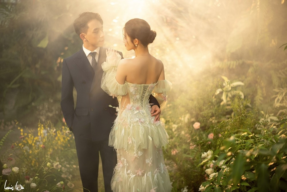 Phương Nhi diện một chiếc váy cưới tông xanh, thiết kế trễ vai, chất liệu voan mỏng nhẹ, được đính kết hoa và họa tiết tinh tế, tạo cảm giác mong manh như nàng thơ. Phần thân váy ôm vừa vặn, tôn lên vóc dáng thon thả, trong khi chân váy bồng bềnh mang lại nét lãng mạn. Ảnh: Louis Wu.