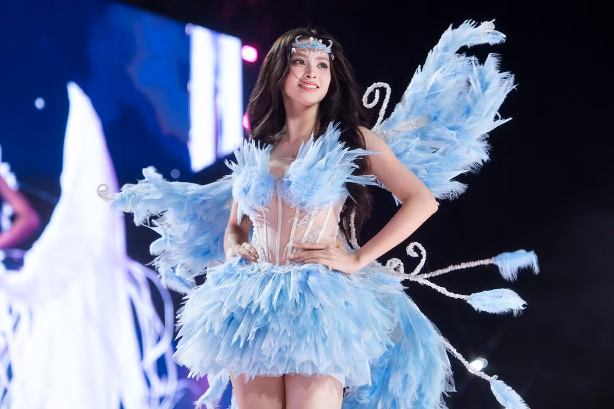 Thiết kế ôm sát phần thân trên, chân váy xòe nhẹ giúp Tiểu Vy khoe vóc dáng thanh mảnh và bước catwalk uyển chuyển trên sân khấu. Đôi cánh lớn phía sau cùng chi tiết uốn lượn ánh kim khiến tổng thể tạo hình của Tiểu Vy thêm phần lung linh, đúng tinh thần nàng tiên sân khấu.