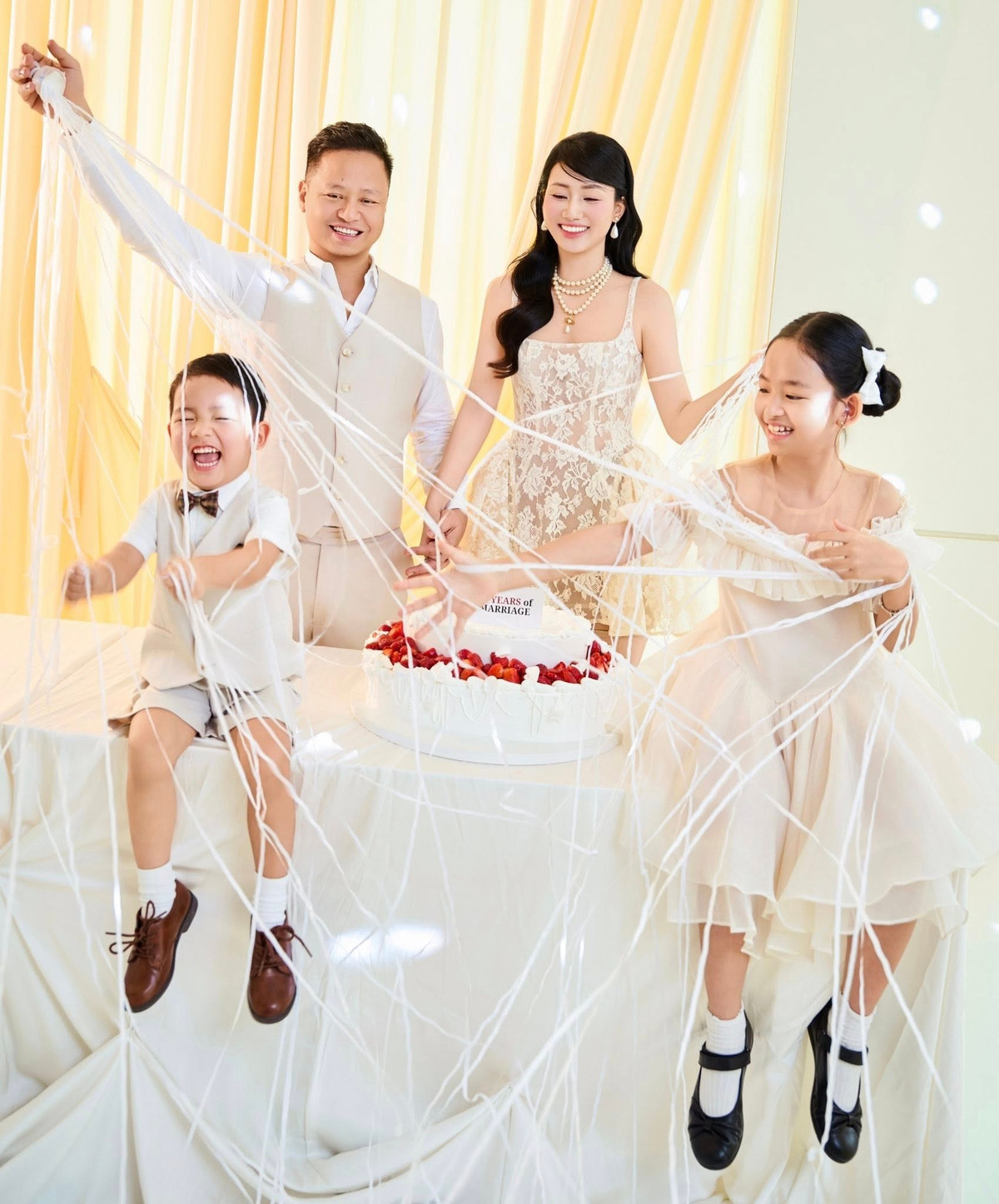 Ở khung hình khác, các con của nàng hậu nghịch ngợm với những sợi dây trang trí, còn vợ chồng Trà My đứng phía sau, lặng lẽ dõi theo.