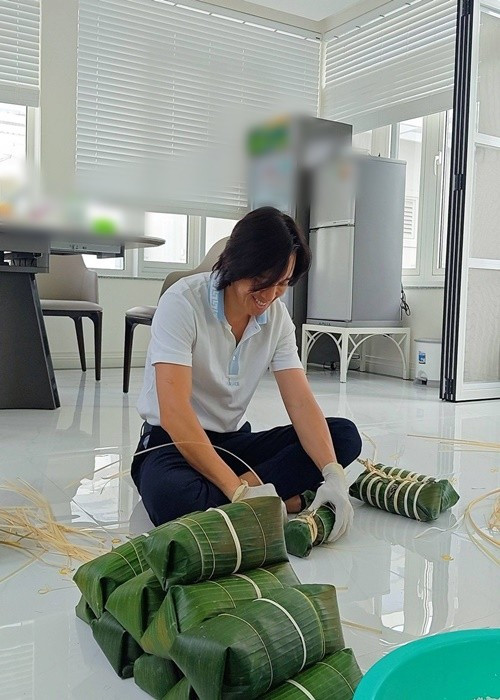 Hoài Phương bày tỏ sự xúc động khi đón tuổi mới đúng dịp Tết. Anh cho biết đây là lần đầu tự tay gói bánh tét. “Nay sinh nhật mình, ngay dịp Tết được cô tổ chức gói bánh thấy ấm áp. Lần đầu mình gói được bánh tét. Áo hồng kế bên gói được luôn đấy mà không biết vớt ra sẽ thế nào. Đợi thành phẩm các bác nhé”, nam nhạc sĩ viết. Ảnh: FB Việt Hương.