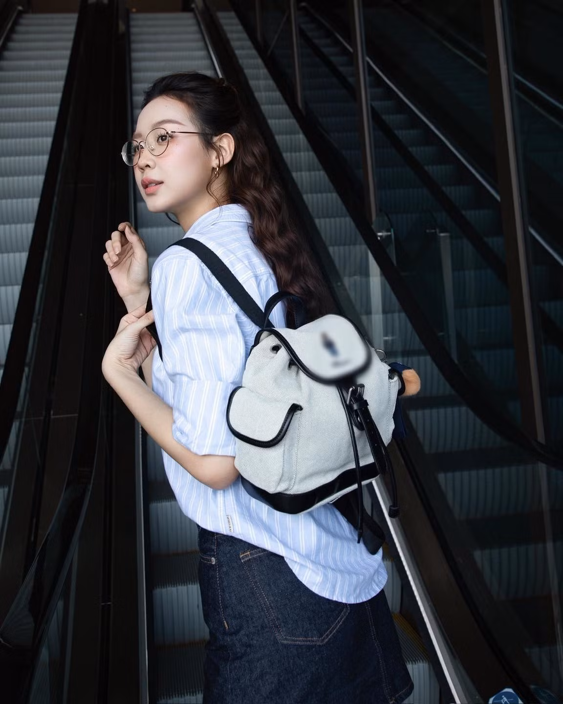 Phụ kiện kính gọng mảnh và túi xách mini tông trắng, vừa tạo điểm nhấn tinh tế, vừa giữ sự hài hòa cho trang phục.