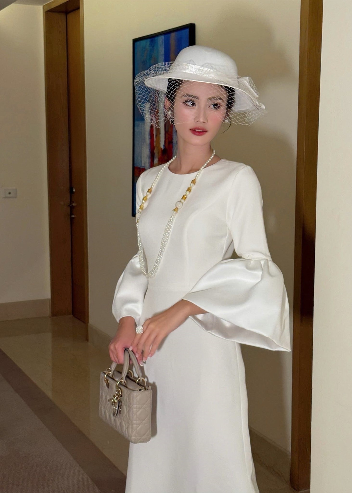 Ngày thứ 16 tham gia cuộc thi Miss World 2025, Hoa hậu Ý Nhi diện set đồ trắng thanh lịch kết hợp với phụ kiện mũ đính lưới, vòng cổ ngọc trai. Ảnh: FB Ý Nhi.