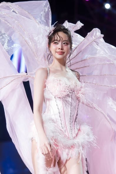 Phần thân váy được điểm xuyết lông vũ mềm mại, kết hợp đôi cánh lớn phía sau bằng chất liệu xuyên thấu, tạo hiệu ứng bay bổng và huyền ảo dưới ánh đèn sân khấu.