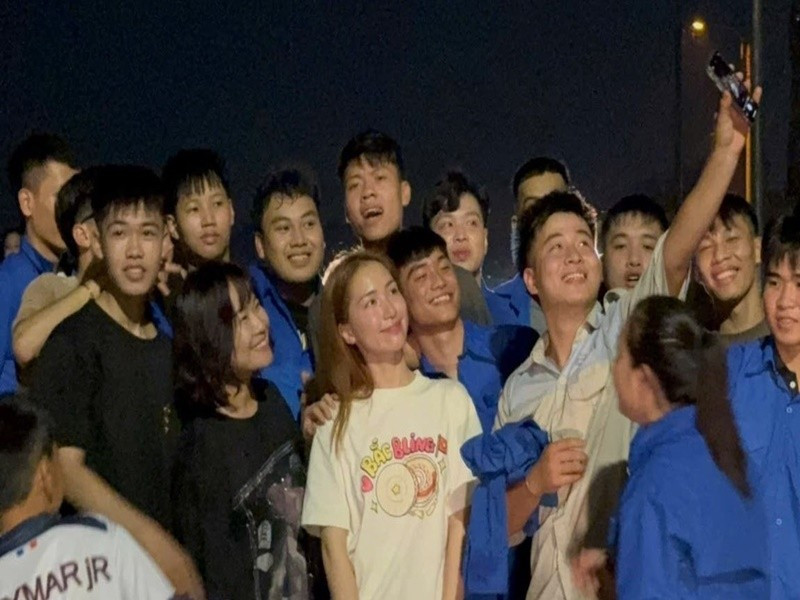 Nữ ca sĩ chụp ảnh kỷ niệm cùng đoàn viên thanh niên tham gia đắp đê. Ảnh: Tiền Phong.