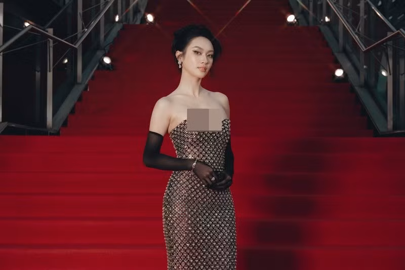 Xuất hiện trên thảm đỏ với đầm cúp ngực đính kết, Vũ Thúy Quỳnh chọn phụ kiện tối giản. Giữa không gian bậc thang đỏ rực, cô không bị “nuốt dáng”.