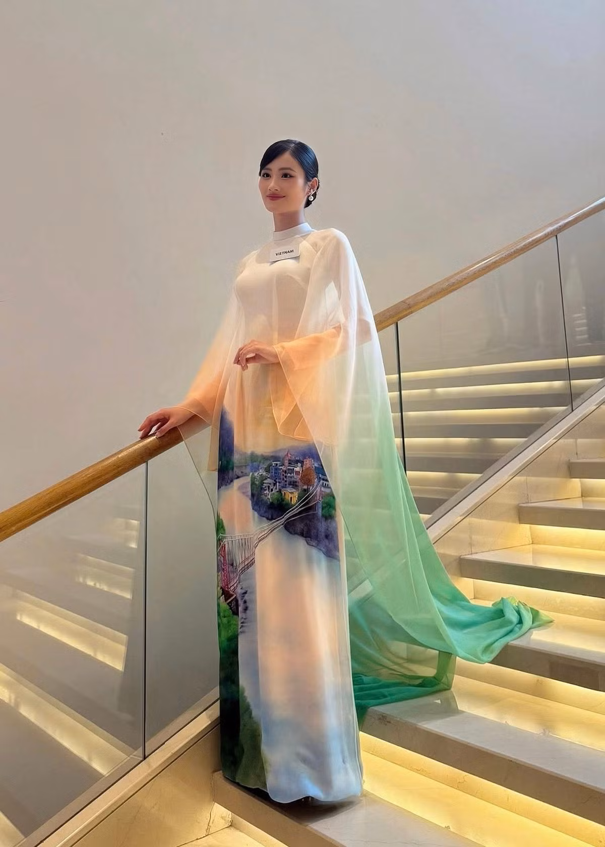 Ý Nhi nói thêm: “Điểm độc đáo và đầy ý nghĩa chính là hình ảnh sông Hằng, một biểu tượng văn hóa thiêng liêng và trù phú của Ấn Độ, được vẽ thủ công một cách sống động và tinh tế. Sự kết hợp hài hoà giữa các gam màu xanh lá, trắng và cam không chỉ tạo nên vẻ nhẹ nhàng, thanh lịch mà còn là sự liên kết ý nhị với màu sắc trên quốc kỳ Ấn Độ. Bên cạnh tôn vinh vẻ đẹp Ấn Độ, chiếc áo dài còn thể hiện sự giao thoa văn hóa sâu sắc giữa hai quốc gia đồng thời gửi gắm sự trân trọng và tình cảm của Ý Nhi cũng như NTK Trung Đinh đối với đất nước, con người nơi đây”. Ảnh: FB Ý Nhi.