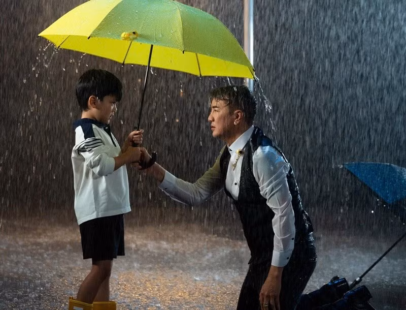 Trong MV, bé Polo che ô cho bố trong cơn mưa tầm tã. Đàm Vĩnh Hưng chia sẻ trên Pháp Luật TPH CM, ban đầu, anh chọn hình ảnh người mẹ, người phụ nữ để xuất hiện trong MV, nhưng cuối cùng con trai lại xuất hiện, bởi với anh, bé Polo là người gần gũi, là động lực động viên anh trong những ngày “bão tố”. Ảnh: FB Polo Huỳnh.