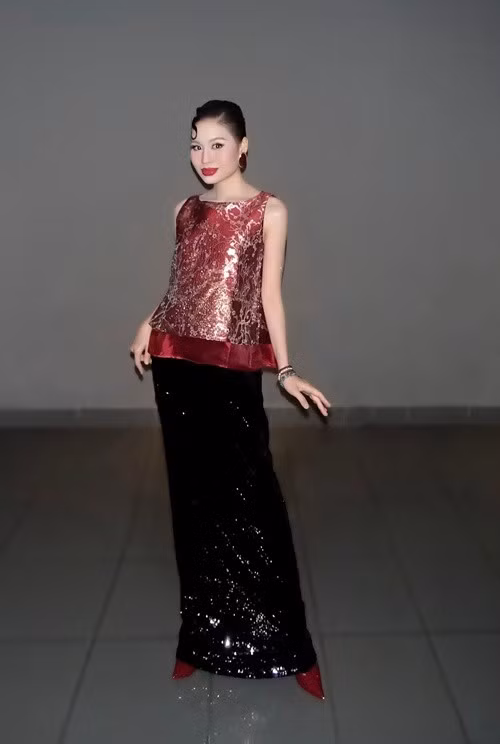 Thiết kế đỏ ánh kim và chân váy sequin trong loạt ảnh giúp Lê Lộc nổi bật ở phần trên cơ thể. Ánh sáng bắt vào chất liệu khiến tổng thể rực rỡ, người xem dễ bị thu hút bởi màu sắc và phong cách hơn là dáng vóc.