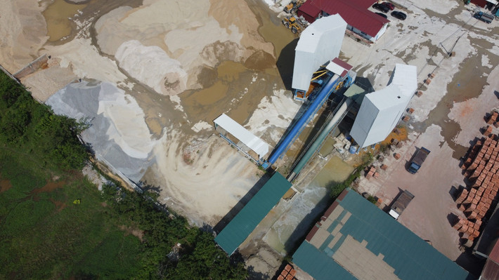 Trạm trộn bê tông đang hoạt động, nước thải trong quá trình sản xuất được xả ra một rãnh nước dài, rộng. Nhìn từ trên cao, nước thải có màu trắng đục, nổi lên đặc sánh váng xi măng.