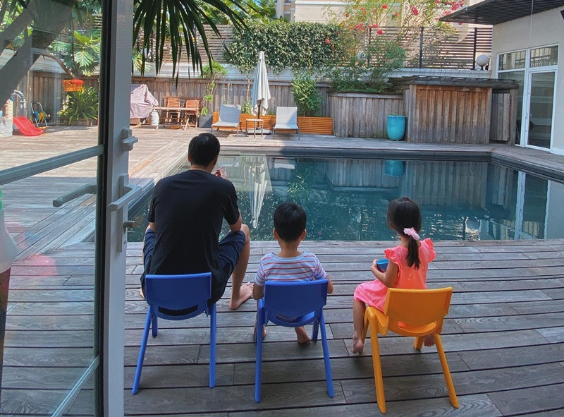 Nam doanh nhân cùng các con ăn kem bên bể bơi.