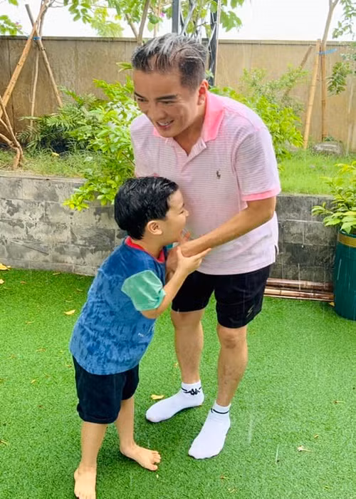 Gần đây, nam ca sĩ chia sẻ hình ảnh cùng con trai tắm mưa ở sân vườn. Ảnh: FB Đàm Vĩnh Hưng.