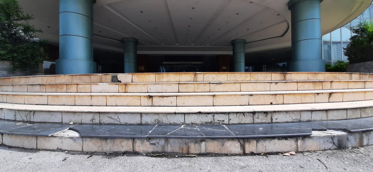 Phần bậc thang đi vào cửa chính tòa nhà cũng bị hư hỏng, bong tróc gạch lát, hệ thống điện cũng bung tứ tung có thể rơi bất kỳ khi nào.