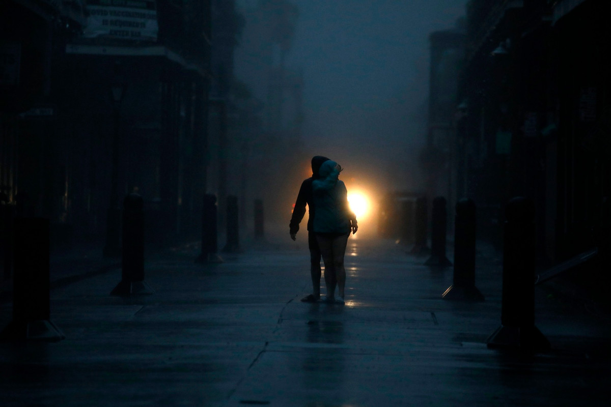 Tổng cộng hơn một triệu hộ gia đình và cơ sở kinh doanh mất điện vào tối 29/8, theo trang web giám sát tình trạng mất điện Poweroutage.US. Trong ảnh, người dân đi trên đường ở New Orleans vào tối 29/8. Ảnh: Bloomberg.