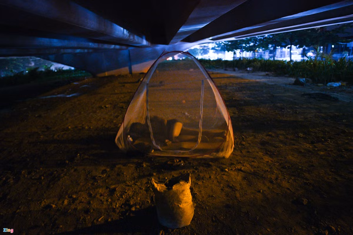 23h30, phía gầm cầu vượt Phạm Văn Đồng, một người lao động dựng vội chiếc mùng rồi ngả lưng.