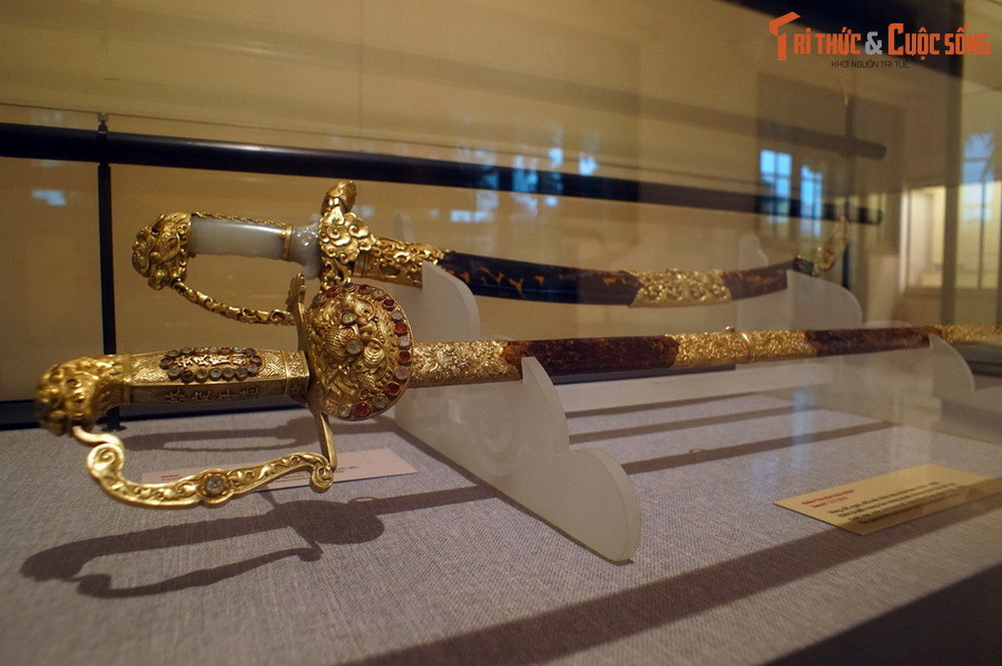 Được bảo quản và trưng bày tại Bảo tàng Lịch sử Quốc gia Việt Nam, bảo kiếm An Dân (thanh kiếm phía dưới trong ảnh) là biểu tượng quyền lực của Khải Định, vị hoàng đế thứ 12 của nhà Nguyễn. Hiện vật đã được công nhận là Bảo vật quốc gia vào ngày 18/1/2024.