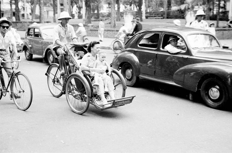 Hai mẹ con người Pháp ngồi trên xích lô.