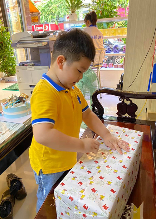 Cậu nhóc thích thú với những món quà của mẹ.