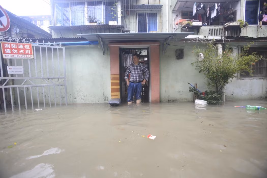 Người đàn ông ngao ngán trông ra đoạn đường ngập lênh láng nước trước nhà.