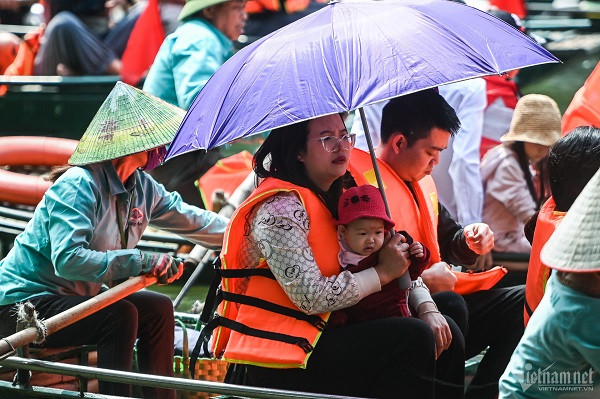 Trời nắng, nhiều gia đình có trẻ nhỏ trang bị thêm ô, trùm kín áo mũ để tránh nắng trong thời gian gần 2 tiếng vãn cảnh.