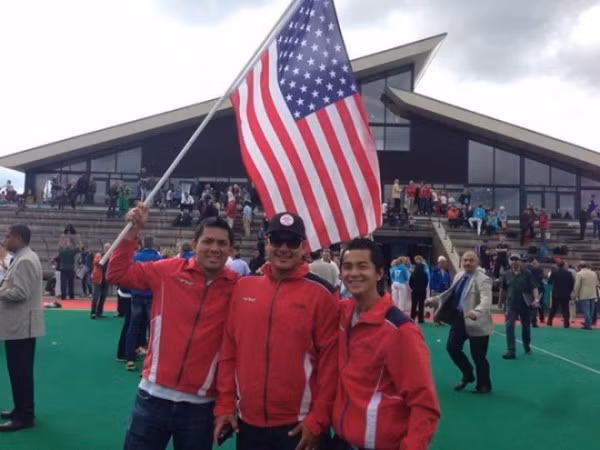 Người hâm mộ thể thao, cộng đồng mạng Việt chắc chắn sẽ phải bất ngờ khi cả hai anh Bình Hoàng và Tommy Hoàng đều là hai tuyển thủ của đội Khúc côn cầu trên cỏ Mỹ, từng tham gia nhiều sự kiện thể thao lớn, mang tầm cỡ quốc tế, toàn cầu cùng đoàn thể thao Mỹ. Trong ảnh là cảnh Bình Hoàng cầm quốc kỳ Mỹ đứng bên Tommy trong giải vô địch khúc côn cầu thế giới năm 2014.