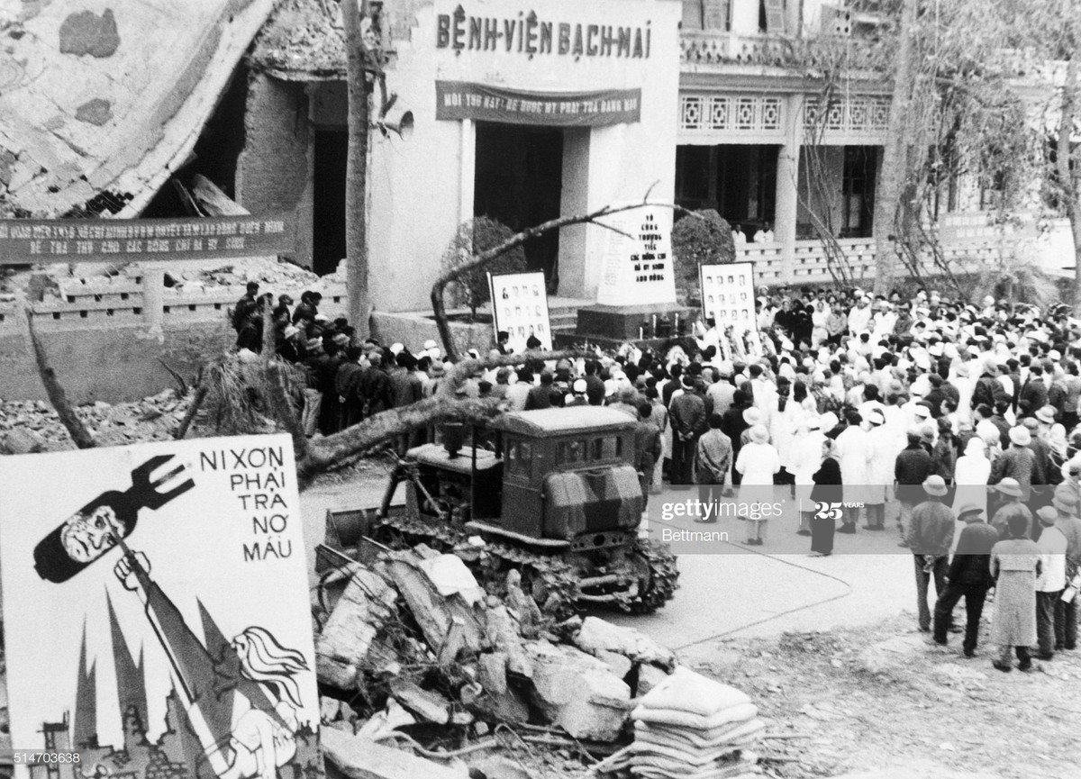Tang lễ cho các y bác sĩ Bệnh viện Bạch Mai hy sinh vì các vụ oanh tạc của B-52 Mỹ diễn ra trước tòa nhà trung tâm của Bệnh viện. Tấm pa-nô "Nixon phải trả nợ máu" được dựng bên đống đổ nát.