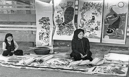 Hai bà cháu ngồi bán tranh dân gian trên phố phường Hà Nội thời xưa.