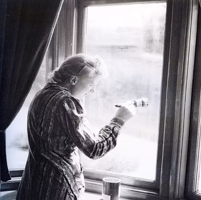 Một bà nội trợ sơn lại cửa sổ năm 1940. Trong các cuộc không kích của phát xít Đức, rất nhiều ngôi nhà bị phá hủy và hư hỏng nặng.