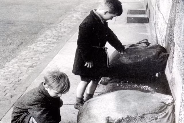 Hai bé trai ở London, Anh chơi bên những bao cát dựng ở ven đường.