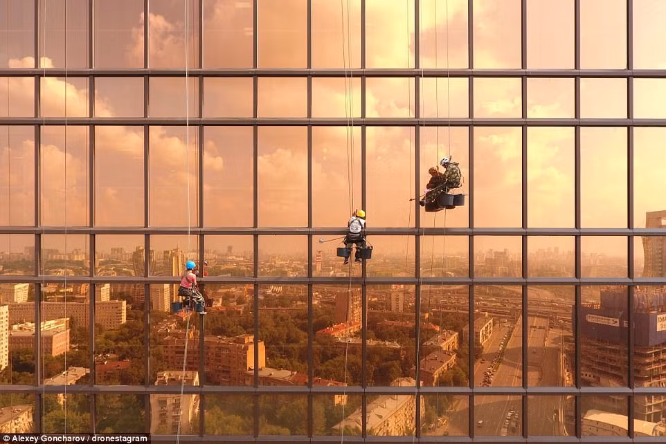 Những người thợ lau kính làm việc chăm chỉ tại Mercury Tower, Moscow, Nga. 