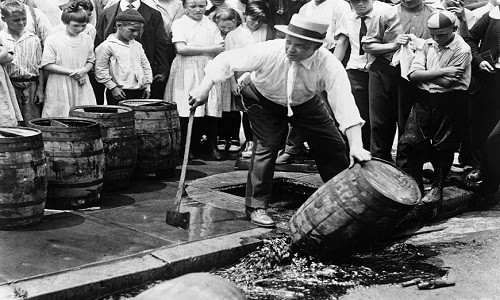 Trẻ em đứng xem những thùng rượu được cảnh sát tiêu hủy trên đường phố.