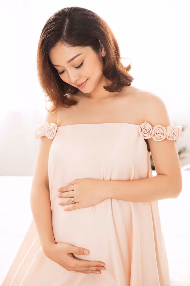 Trang phục đầm bầu màu nude, kết hoa hồng ở tay áo khá phù hợp vẻ nữ tính của người mặc.