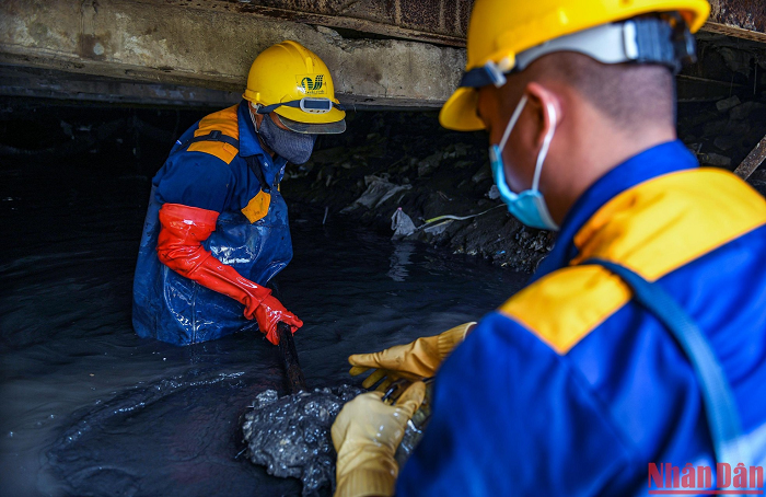 Từng xẻng bùn được chuyển ra phía bên ngoài cho một nhóm công nhân trẻ hơn đang đợi sẵn. 
