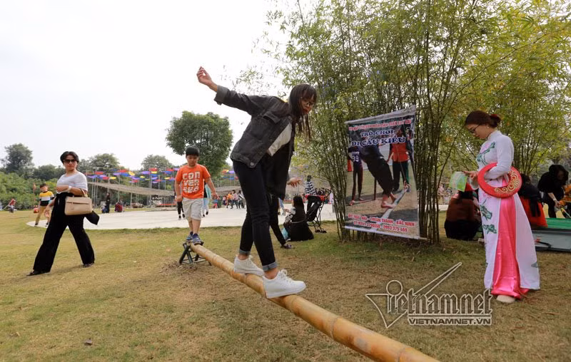 Nhiều bạn trẻ trải nghiệm trò chơi đi thăng bằng trên một cây tre. 