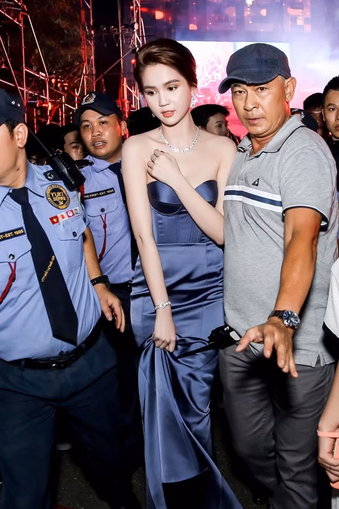 Khuya 31/12/2016, người mẫu Ngọc Trinh gây chú ý khi tham dự sự kiện đếm ngược chào mừng năm mới 2017 diễn ra tại TP.HCM. Cô nổi bật với váy cúp ngực, đeo trang sức kim cương đắt giá. Người đẹp Vòng eo 56 nhận được sự hộ tống kỹ càng từ ban tổ chức. Diễn viên Tùng Yuki (áo ghi) có vai trò đảm bảo an toàn cho Ngọc Trinh. Tài tử Bỗng dưng muốn khóc hiện là giám đốc một công ty vệ sĩ.