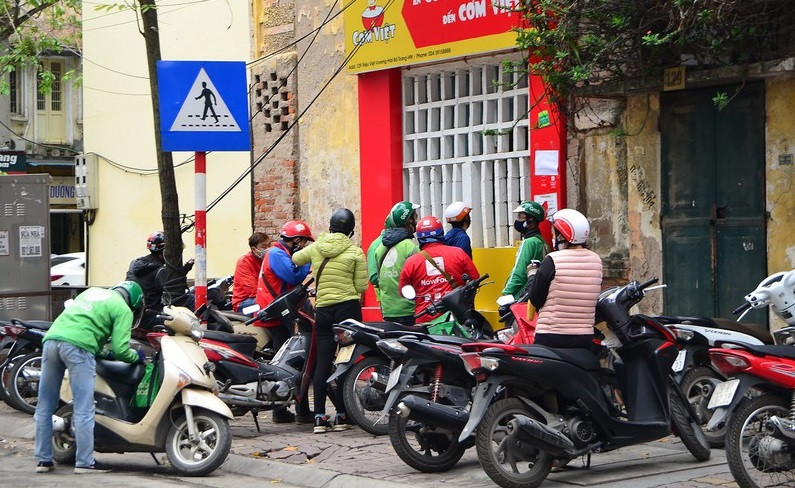 Chia sẻ với báo chí, anh Nguyễn V.M. (23 tuổi, ở quận Hoàng Mai, Hà Nội) đang là shipper tự do tại Hà Nội cho biết: "Trước đây tôi làm giao hàng cho hai shop "ruột" và thỉnh thoảng nhận thêm đơn trên nhóm hội giao hàng. Nhưng mấy hôm nay dịch COVID-19 diễn biến phức tạp, người ta hạn chế đi lại mà chủ yếu mua online nhiều nên số lượng đơn hàng tăng hơn rất nhiều so với trước đó. Hôm nào tôi cũng phải giao hàng từ sáng sớm đến tối mà vẫn chưa hết đơn. Công việc quá tải nhưng thu nhập của tôi lại tăng lên”. (Ảnh: VOV).