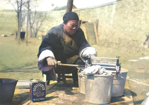 Là người hầu trong một gia đình giàu có, người phụ nữ trong ảnh đang dùng một thiết bị để vắt kiệt nước sau khi giặt quần áo.