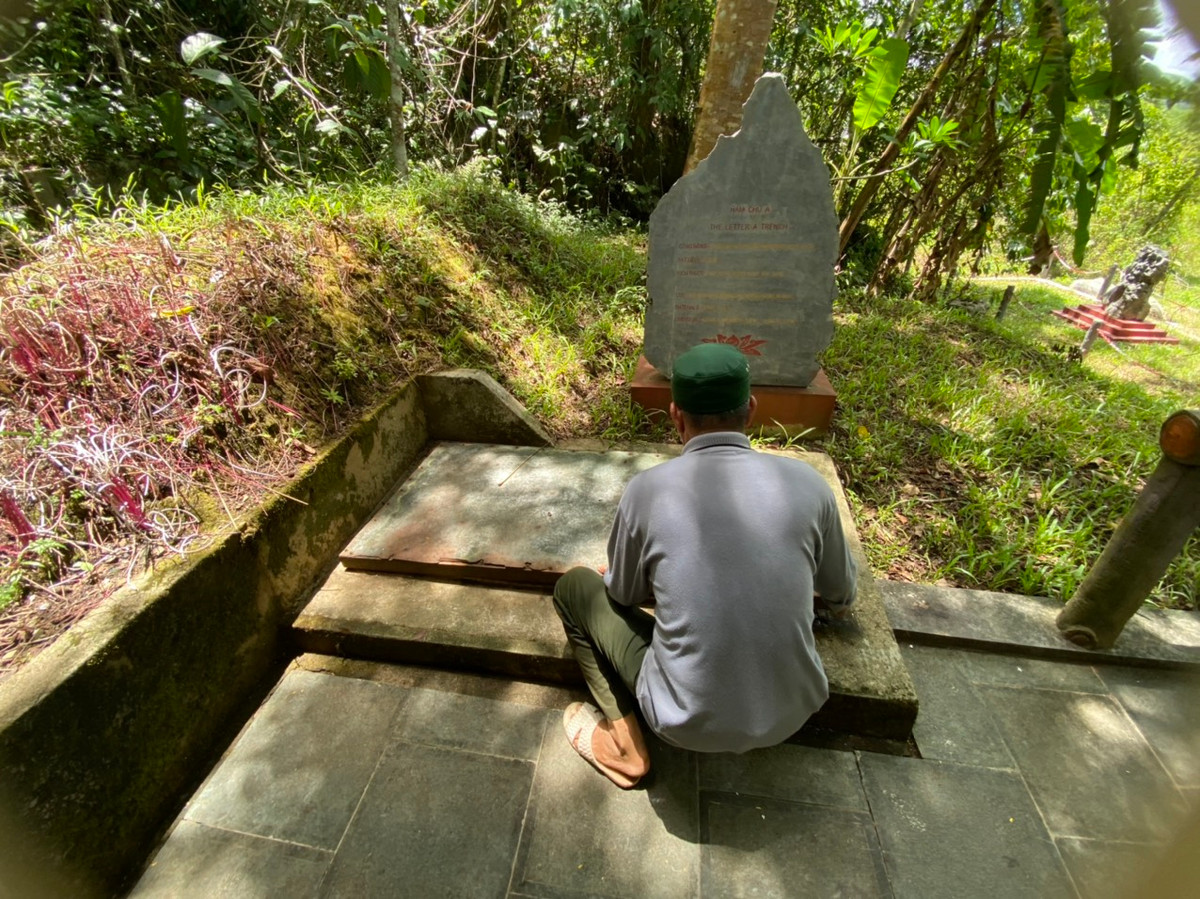 Ông Nguyễn Văn Ba, bảo vệ di tích đang ngồi bên chiếc hầm trú ẩn của những người lính Trạm A69 năm nào. Đây cũng nơi 3 chiến sĩ đã anh dũng hi sinh sau loạt bom của quân thù.