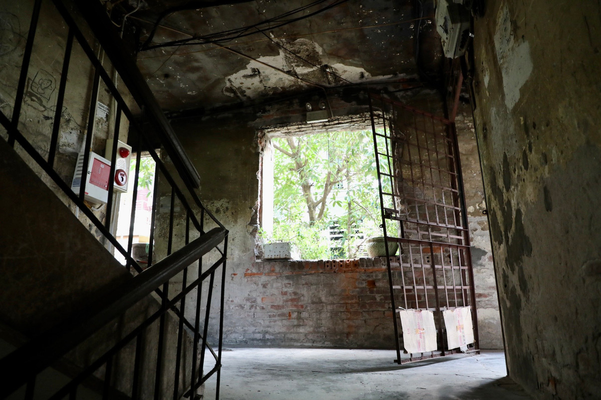 Lối đi lên cầu thang tối tăm. Khung cửa sổ chỉ còn những ô trống.