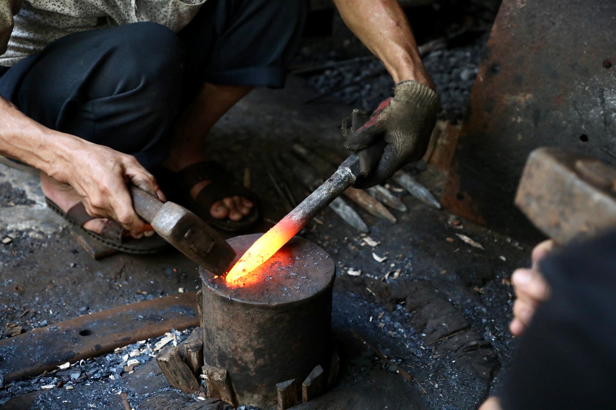 "Để tạo ra được một sản phẩm có chất lượng tốt, phải trải qua rất nhiều công đoạn. Khâu quan trọng và đòi hỏi nhiều kỹ thuật nhất là tôi thép và làm nguội. Đầu tiên, sẽ cắt các bản sắt thành hình dạng của sản phẩm, sau đó cho lên lò nung với nhiệt độ hơn 1.000 độ C. Thời gian nung sẽ tùy vào từng loại nguyên liệu thép và sản phẩm tạo ra dày, mỏng. Khi phôi thép nung chuyển sang màu đỏ trắng là lúc đặt lên đe để quai búa", ông Cung chia sẻ. Ảnh: Rèn mũi khoan bê tông.