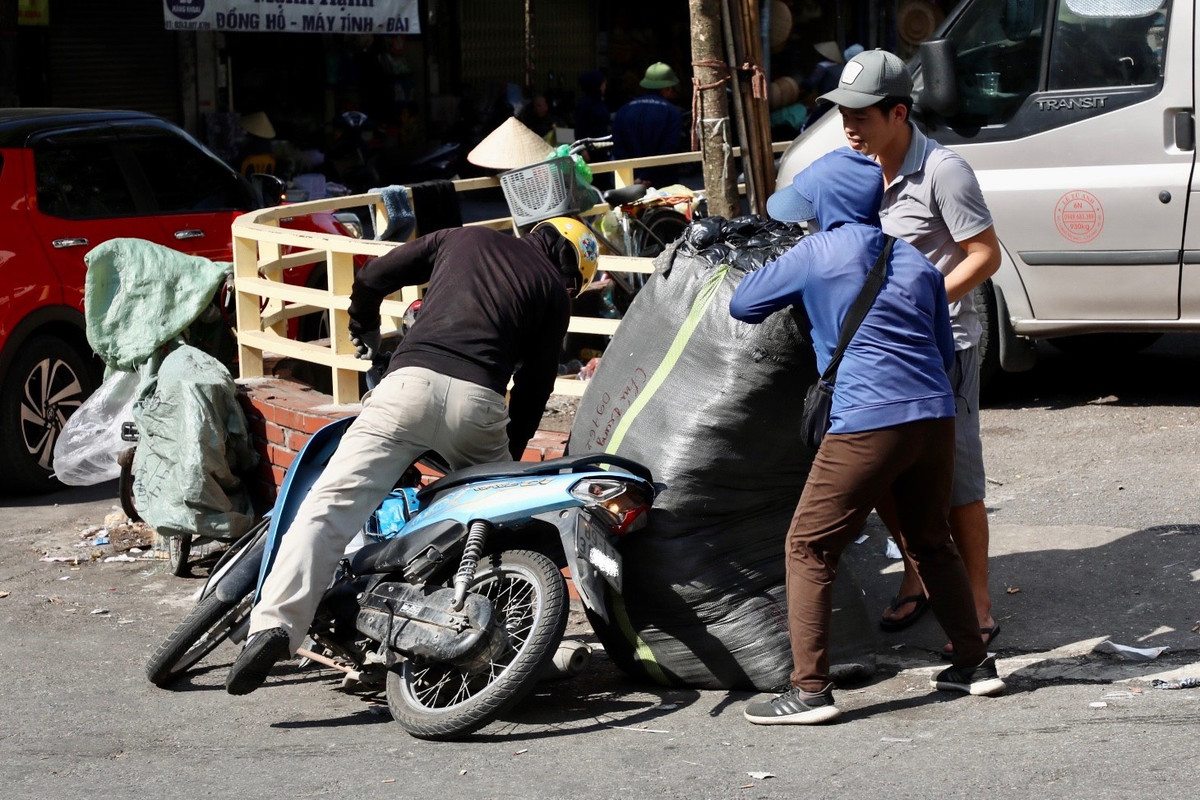 Do bao hàng nặng, khi bốc lên xe máy không cân đối đã khiến cả xe và hàng bị đổ.