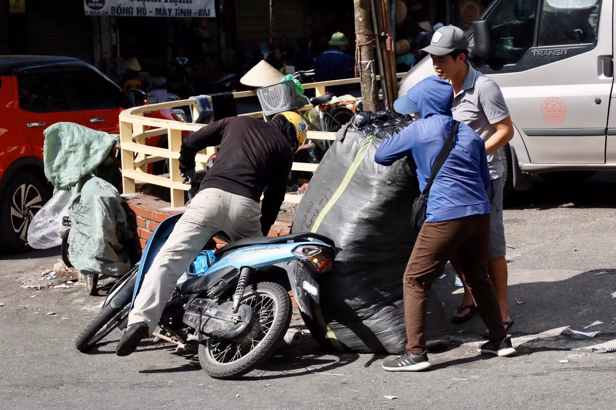 Do bao hàng nặng, khi bốc lên xe máy không cân đối đã khiến cả xe và hàng bị đổ.