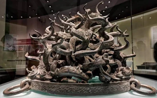 Mặc dù hỗn loạn, sự sắp xếp kỳ công của chúng tạo nên một cảm giác kỳ lạ và chói mắt, hòa quyện giữa sự rõ ràng và sinh động. Các con rồng trên đế đều đang leo lên, và việc chúng quấn quýt vào nhau khiến cho không ai biết chính xác có bao nhiêu con rồng trên đế trống này.