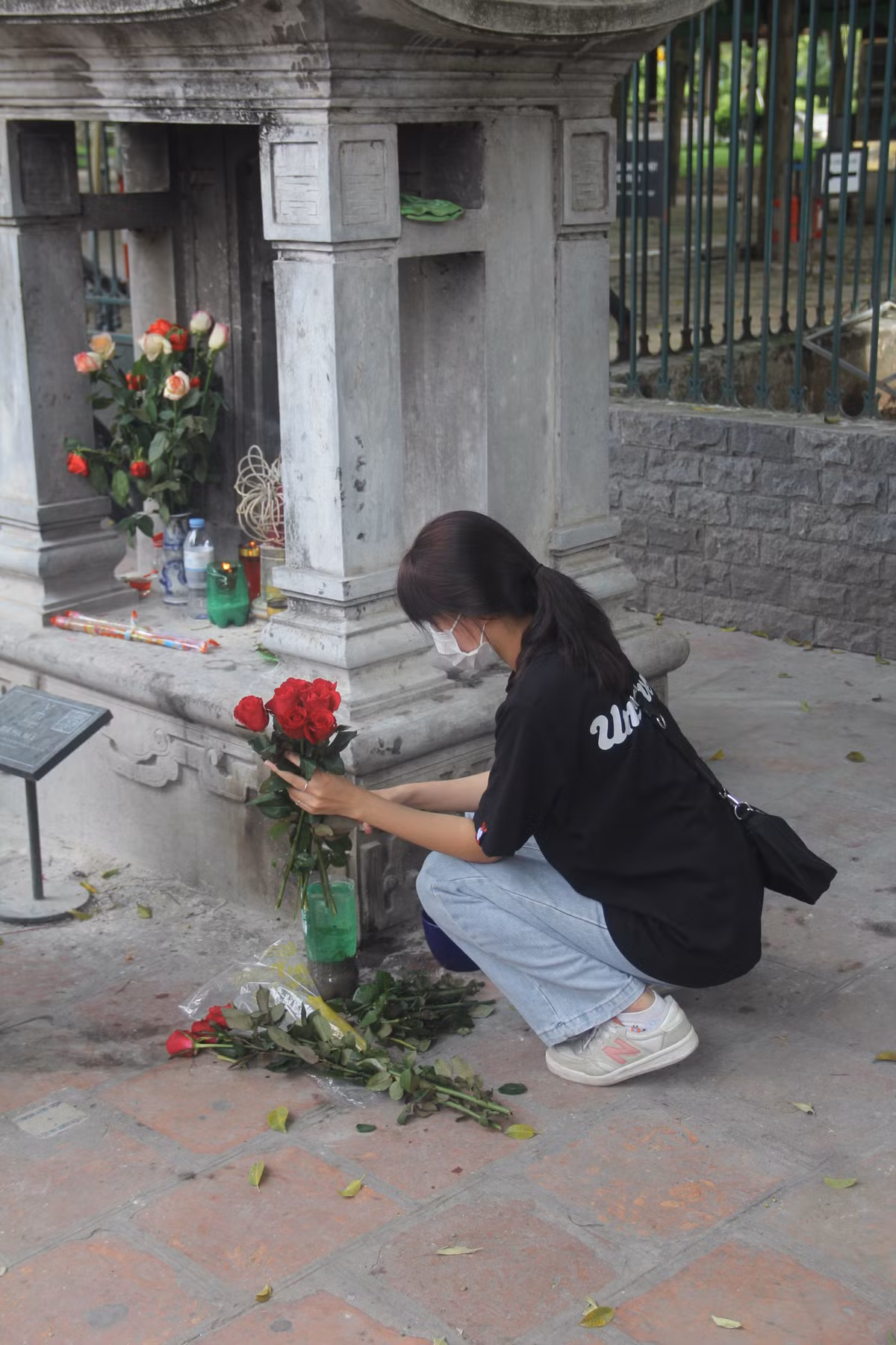 Một học sinh cẩn thận cắm những bông hoa đặt bên ngoài Văn Miếu. Học sinh này chia sẻ, bản thân mong rằng sẽ vượt qua kỳ thi sắp tới và trúng tuyển vào ngôi trường mơ ước.