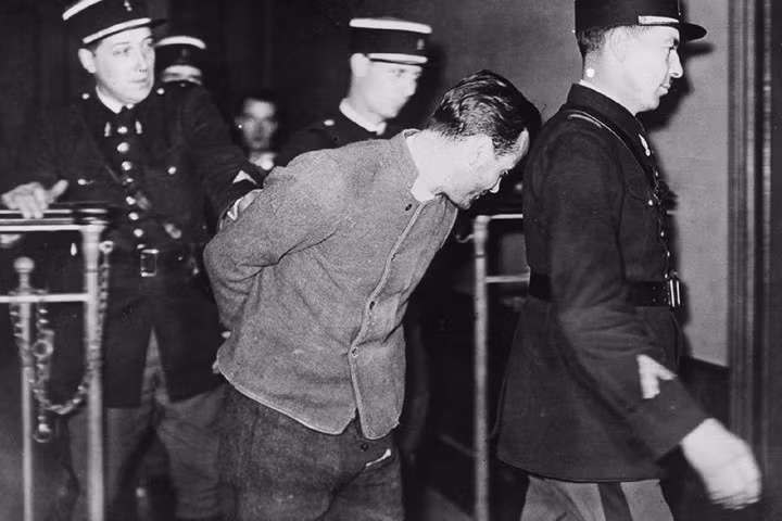 Trong ảnh này, Weidmann bị cảnh sát còng tay dẫn đi sau khi y bị bắt.