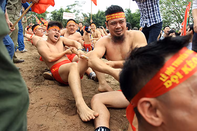 Mỗi người một tay duỗi thẳng, tay kia co trước ngực, song được kẹp chặt dưới nách của tay co. Mọi người vừa hô kéo co vừa hô vang “í a, kéo.”