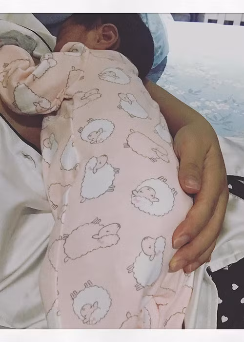 Bé Tuệ An nằm ngoan ngoãn trong vòng tay ấm áp của mẹ. Lúc này, cô nhóc tròn 3 tuần tuổi. Ảnh: FBNV