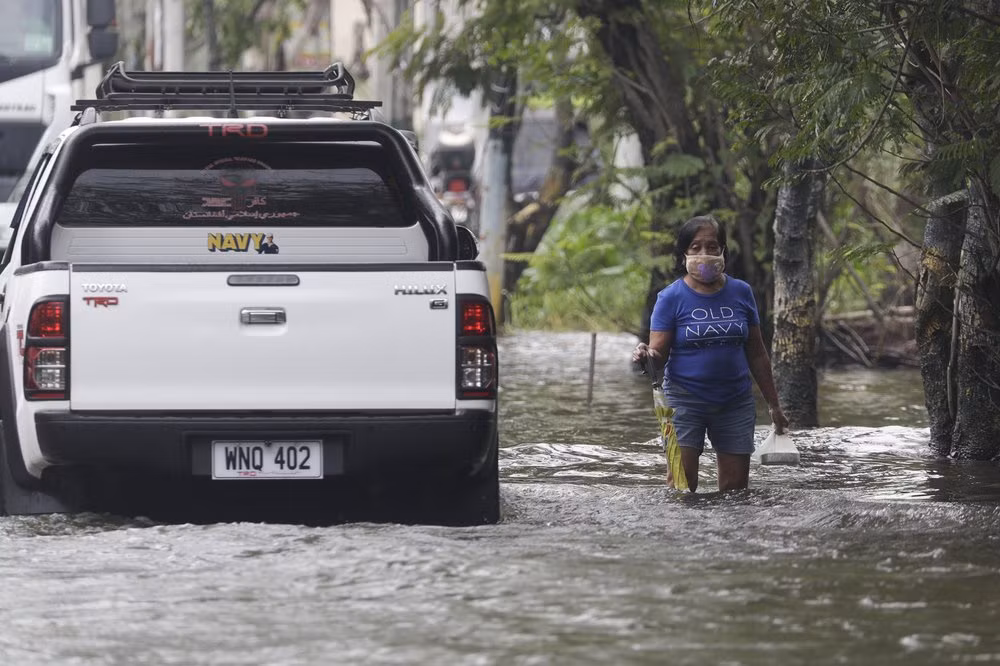 Người phụ nữ đi trên con đường bị ngập do bão Molave ở tỉnh Pampanga, miền bắc Philippines, hôm 26/10.