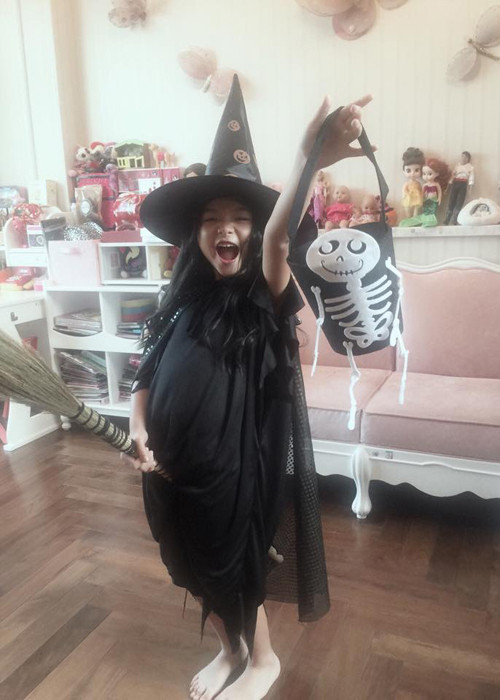 Cô bé khoác áo choàng đen, đội mũ nhọn và cưỡi chổi. Để đúng với không khí ngày lễ Halloween, Bảo Tiên còn được mẹ chuẩn bị thêm chiếc túi có in hình bộ xương.