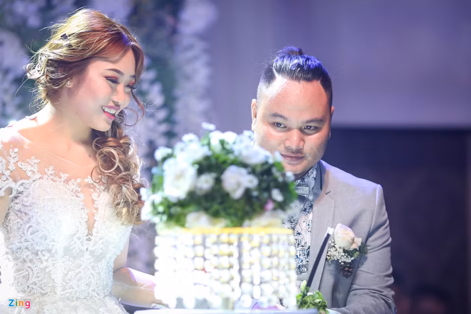 Cô dâu chú rể cắt bánh cưới trước sự chứng kiến của quan khách.